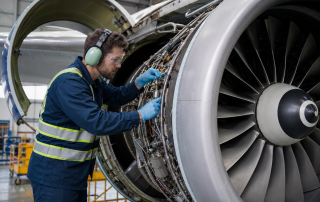 Técnico de mantenimiento aeronáutico revisando el motor de turbina de un avión comercial en hangar